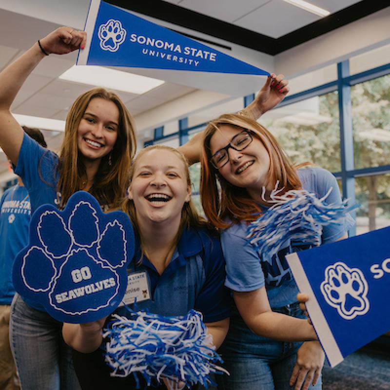 Three female students cheer while wearing SSU blue gear