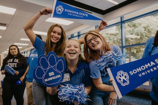 Three female students cheer while wearing SSU blue gear