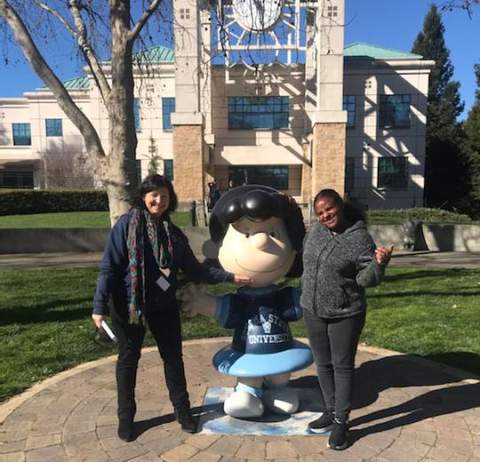 photo of two people standing next to Peanuts character Lucy statue