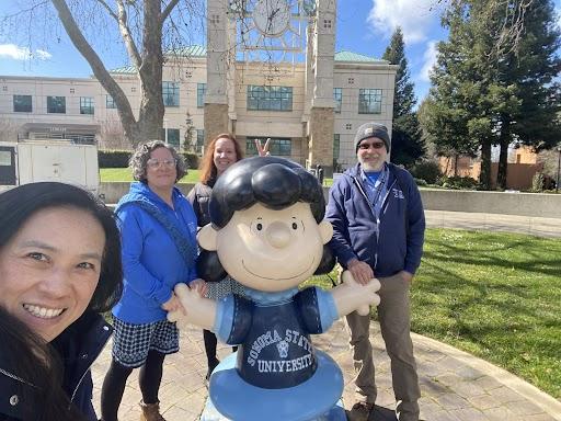 photo of 4 people surrounding statue of Peanuts character Lucy