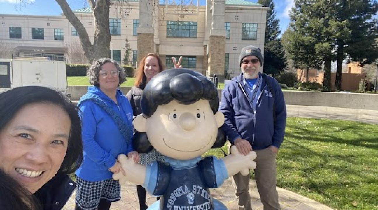 photo of 4 people surrounding statue of Peanuts character Lucy